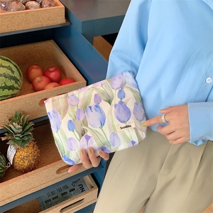 Detail of floral tulip canvas makeup bag with blue zipper and vintage style brand label