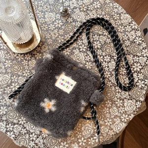 Detail of plush grey crossbody bag with floral patterns and a rope shoulder strap