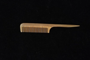 Detailed view of the fine teeth and natural wood grain on the green sandalwood comb