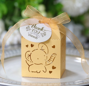 Detail of yellow hollow elephant favor box with silk ribbon and Thank You tag