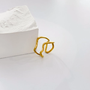 Close-up of golden wave ring with layered twisted lines leaning on a white textured stone