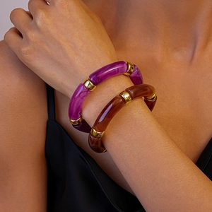 Gros plan de bracelets en acrylique violet et ambre empilés avec des anneaux dorés