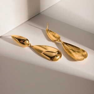 Macro shot of minimalist gold teardrop earrings with high-polish finish and modern shadows