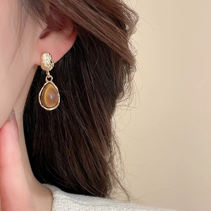 Détail de boucles d'oreilles vintage en résine en forme de goutte sur un modèle élégant