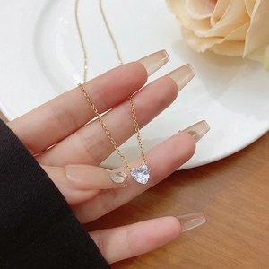 Detail of heart crystal necklace in 18k gold plated titanium steel held by hand