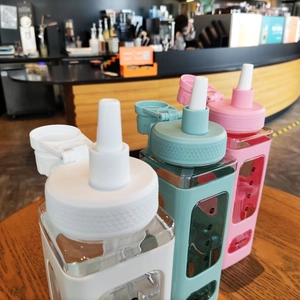 Detail view of square plastic sports bottles with silicone sleeves and capacity markings