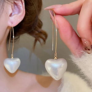Close-up of a model wearing the heart-shaped pearl drop earrings with gold hooks