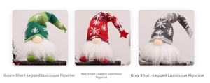 Close-up of three glowing Christmas gnomes in green red and grey with snowy knit hats