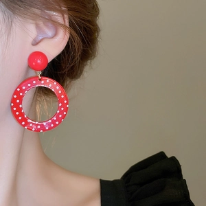 Close-up of red polka dot resin hoop earrings on model featuring retro pop style design