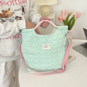 Detail van mintgroene gewatteerde canvas tas met hartpatroon en roze schouderbanden