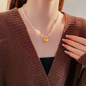 Vintage pearl necklace featuring a gold lucky bag pendant worn on a model's collarbone