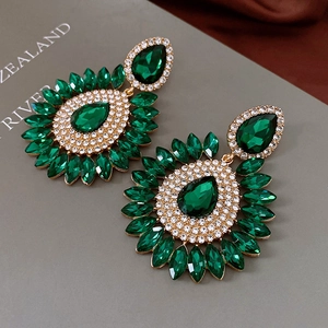 Gros plan de boucles d'oreilles vintage avec cristal émeraude et strass argentés sur livre
