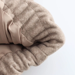 Detail of soft beige wool blend fabric and smooth inner lining on a bomber jacket