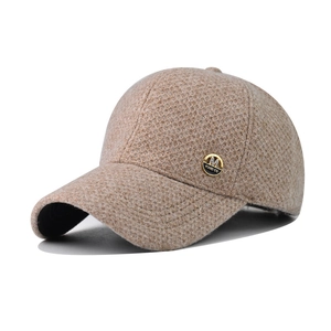 Detail of light brown knitted baseball cap featuring a premium gold metallic M logo badge