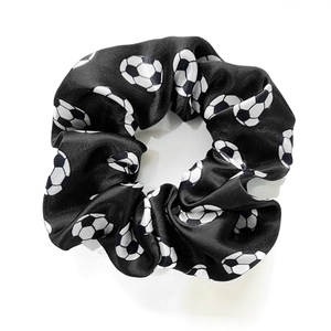 Detail shot of a black and white soccer print satin scrunchie with a silky texture
