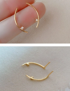 Detail view of a dainty gold curved C-shape stud earring with a tiny white zircon