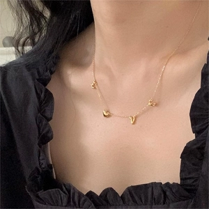 Close-up of golden LOVE letter pendant necklace worn on neck with elegant black top