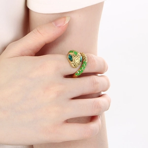 Macro detail of golden snake ring featuring green enamel scales and emerald eyes