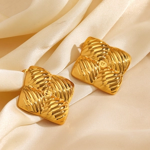 Elegant gold square stud earrings with geometric stripe pattern on beige silk background