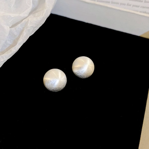 Macro shot of silver ball stud earrings with brushed matte texture on black velvet