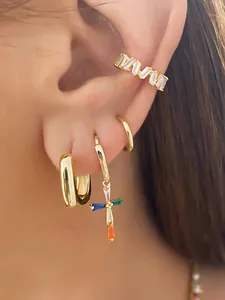 Detailed close-up of golden ear cuff set featuring colorful rhinestone cross pendant and rings