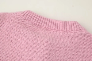 Detail shot of the ribbed round neckline and fine knit texture of pink cardigan
