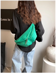 Green nylon crossbody chest bag with wide strap shown on model's back in a casual style