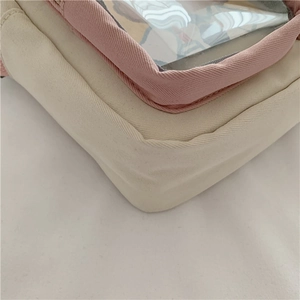 Detail of canvas shoulder bag with pink piping and clear PVC window design