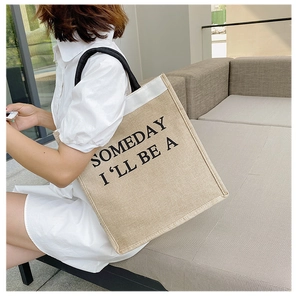 Close-up of retro linen tote bag with SOMEDAY I'LL BE A print and sturdy black handles