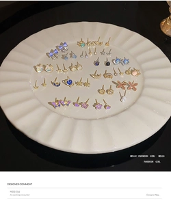 Exquisite assortment of butterfly and floral stud earrings on a white ceramic display tray
