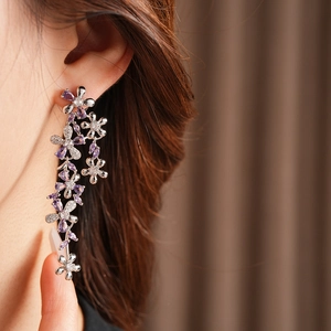 Detailed close-up of long tassel flower earrings with purple zircons on a female model