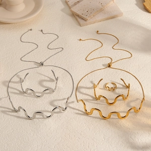 Detail of minimalist wavy jewelry set with adjustable necklace and open bangle in gold and silver