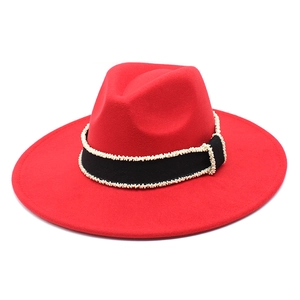 Detail of red wool felt fedora featuring a black ribbon with delicate white bead accents