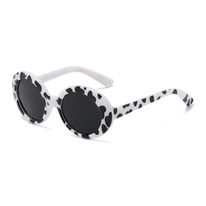 Detailed close-up of cow print round pet sunglasses with dark grey lenses and plastic frame