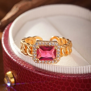 Macro detail of a gold Cuban chain ring with a red rectangular zircon and pavé border