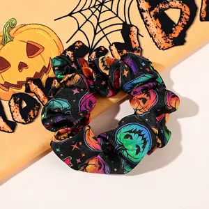 Detail of Halloween pumpkin print scrunchie with colorful stars on glossy satin fabric