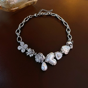 Detail view of silver charm bracelet featuring pearl heart, strawberry and rose charms