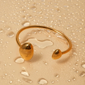 Bracciale rigido aperto irregolare in acciaio placcato oro 18k con estremità a ciottolo