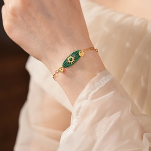 Détail d'un bracelet vintage en chaîne dorée avec pierre de malachite et emblème soleil