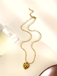 Detail of gold-plated chain with heart pendant and colorful inlaid gemstones
