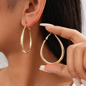 Close-up of polished gold-finish teardrop hoop earrings on model for detailed look