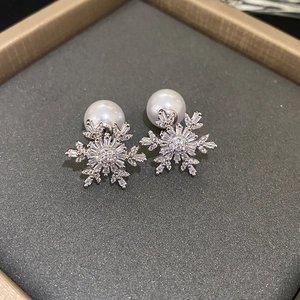 Pendientes de copo de nieve plateados con circonitas y perlas blancas en un estuche