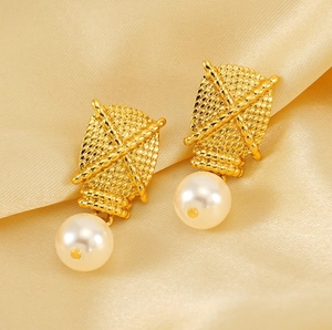 Macro detail of gold braided texture earrings with elegant round white pearls