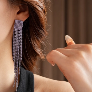 Gros plan de boucles d'oreilles pampilles violettes avec strass sur l'oreille du mannequin