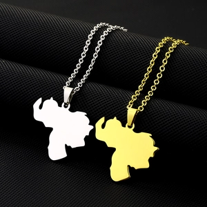 Close-up of Venezuela map pendants in gold and silver finish on textured black background