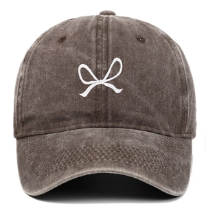 Macro detail of white bow embroidery on vintage washed cotton baseball cap in dark brown