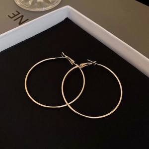Gros plan de boucles d'oreilles créoles dorées minimalistes dans un coffret cadeau