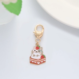 Cute enamel keychain with a cartoon cat on a strawberry cake and gold heart clasp