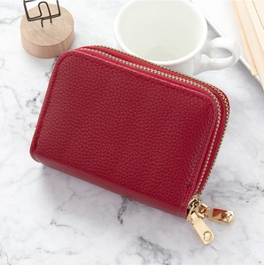 Detalle de cartera de cuero lichi rojo con cremalleras doradas dobles y compartimentos
