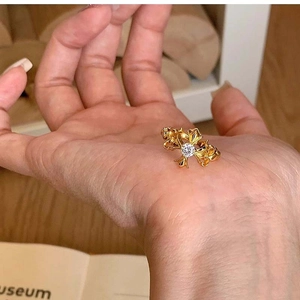 Detail of vintage gold iris flower ring with central stone held in hand over a desk